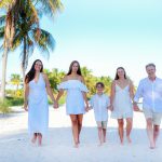 Family smiling on Smathers Beach at sunset with palm trees in the background.