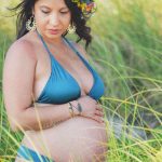 Expecting mother in a flowing dress poses under palm trees on Smathers Beach with turquoise ocean behind her.